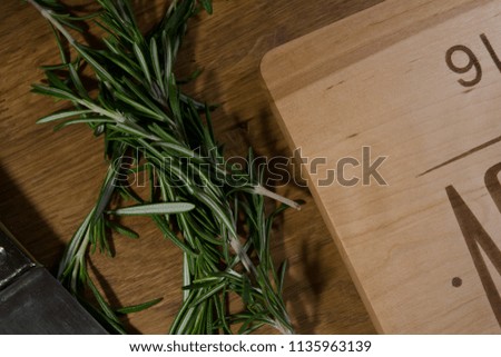 Engraved cutting board with rosemary on a wooden kitchen table. High quality great photo.