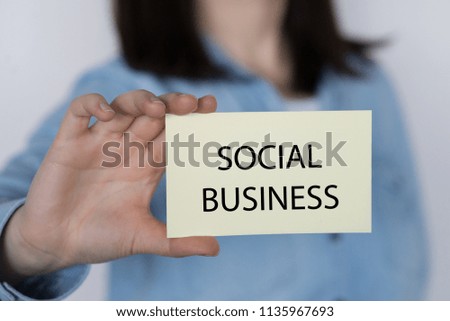 SOCIAL BUSINESS message on a yellow card hold by a business woman, business concept image with soft focus background