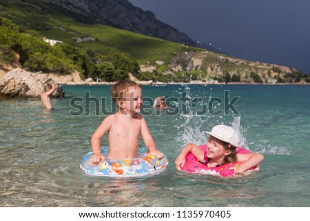 happy children play and swim in the sea. Thunderstorm begins, stormy sky