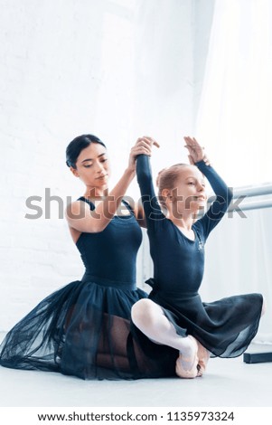 beautiful young ballet teacher training adorable flexible kid in ballet school 