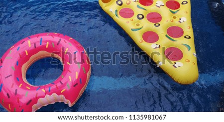 
Pizza and donut design inflatable toy floating in the swimming pool, summer vibe. Background / Textures