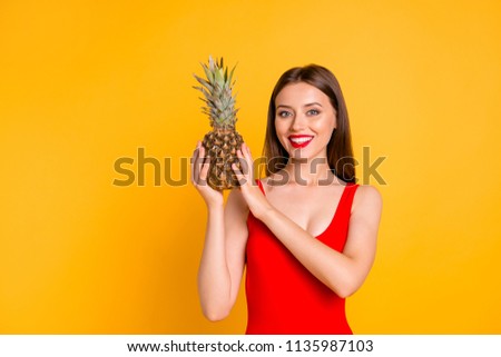 Beach style! Charming girl holding a pineapple in her hands isolated on bright yellow background