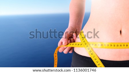 Digital composite of Woman measuring weight with measuring tape on waist on Summer beach