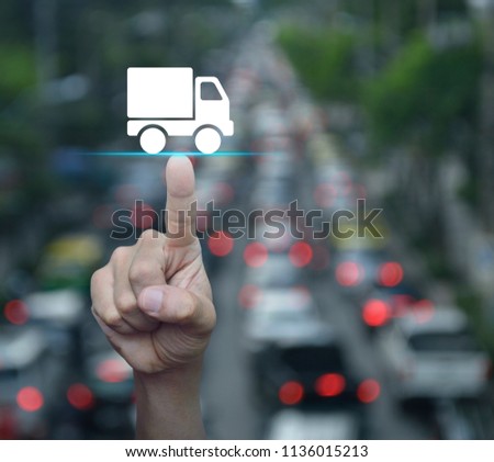 Hand pressing truck delivery icon over blur of rush hour with cars and road, Business transportation service concept