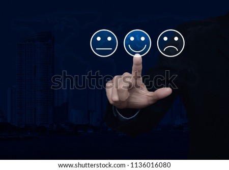 Businessman pressing excellent smiley face rating icon over world map and modern city tower, Business customer service evaluation and feedback rating concept, Elements of this image furnished by NASA