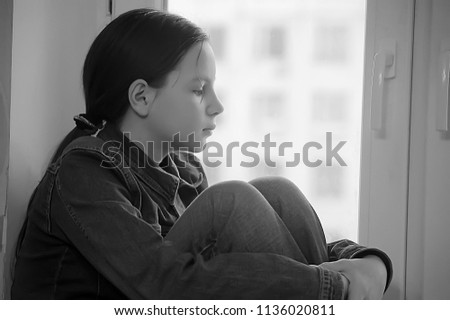 Sad girl sitting on a window sill in depression