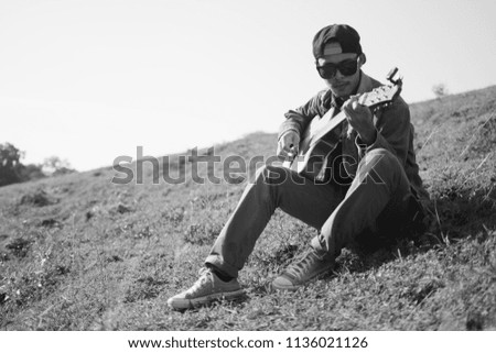 Young guitarist with fun amid green meadows.