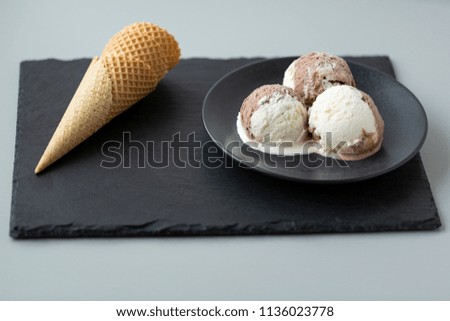 Chocolate and vanilla ice cream, waffle cones, dark stone background