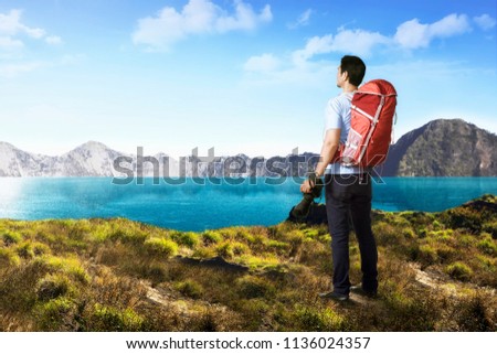 Handsome asian photograper man with backpack and camera on the mountain