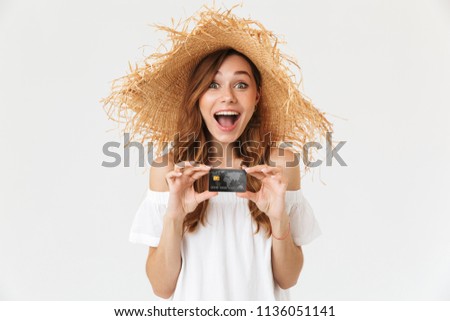Photo of excited pretty woman 20s wearing big straw hat smiling and showing credit card isolated over white background