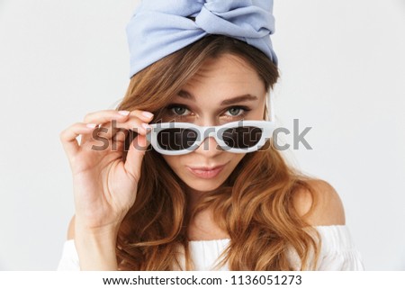 Portrait closeup of stylish adorable woman 20s looking at camera from under sunglasses isolated over white background