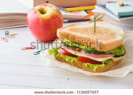Snack for school with sandwich, fresh Apple and orange juice. Colorful school supplies