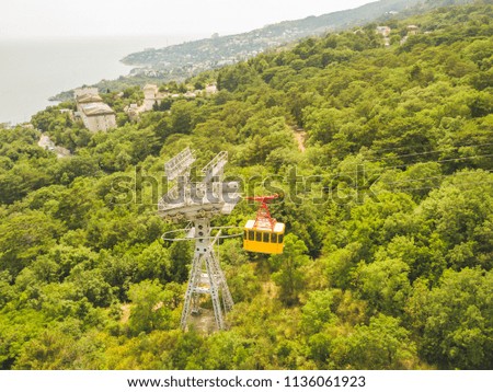 aerial top view of cable car cabin moving to the top of mountain on a summer day