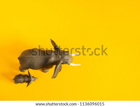 Plastic figurine of Elephant and a small elephant of animals of hot countries. Protection of the animal. Children's toy. Yellow background.