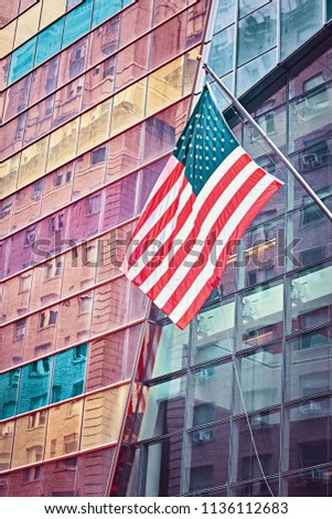 Color toned picture of an American flag in front of a modern building, New York City, USA.
