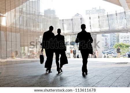 Three business people walking down the street talking. Silhouettes. Motion Blur.
