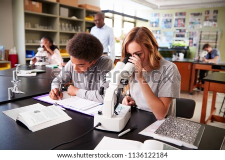 High School Students Looking Through Microscope In Biology Class Royalty-Free Stock Photo #1136122184