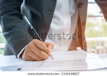 Document Report and business busy Concept: Businessman Manager checking and signing documents reports papers with calculator, laptop computer on stacks of paper files in modern office.  