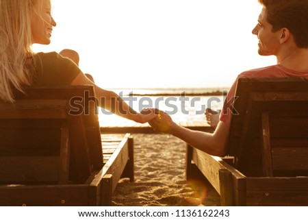 Picture of friends loving couple have a rest outdoors on the beach.