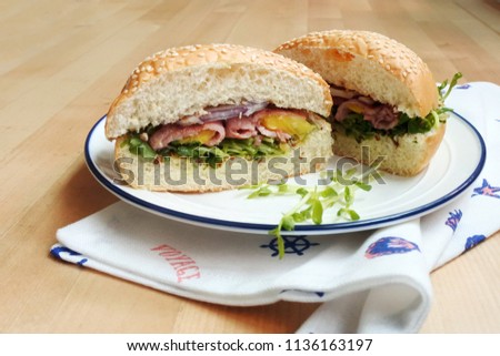 Summer Hawaii bacon and pineapple burger with purple onion and sprout (cut in half, white plate, wooden table, white fabric placemat with sea patterns)