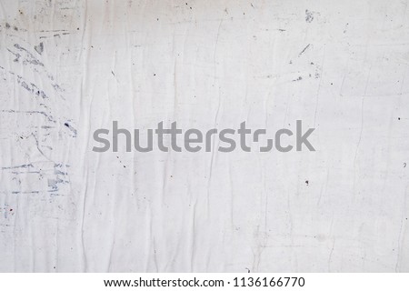 white grey street poster glued to a wall with wheat paste, empty rippled wrinkled creased paper texture Royalty-Free Stock Photo #1136166770
