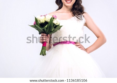 cropped shot of young bride in wedding dress with bouquet isolated on white