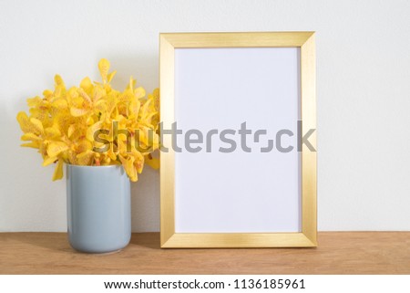 Gold frame with yellow orchid flowers on table