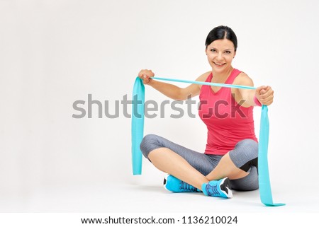 Brunette woman doing exercises with rubber band, fitness studio concept