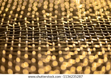 Metal grid. Lattice made of steel. Shallow depth of field. Yellow bokeh from sunset
