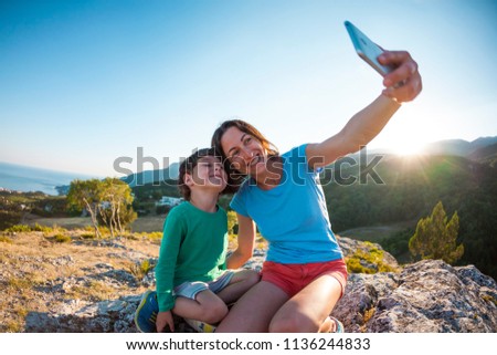 A woman with a boy on top of a mountain. Mother and son make selfie on the background of a beautiful landscape. Traveling with a child. Overnight in the countryside.