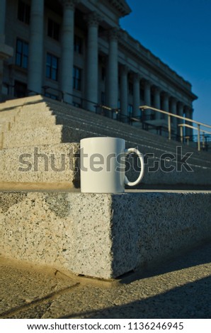 A blank white coffee mug on the capitol hill steps under the morning sun waiting for the law. 