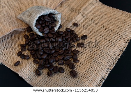 Brown roasted coffee beans on old bag background.