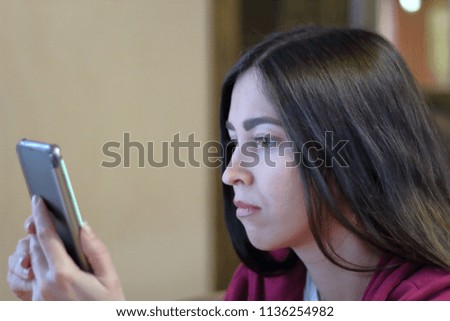 girl with a serious face looking at the phone
