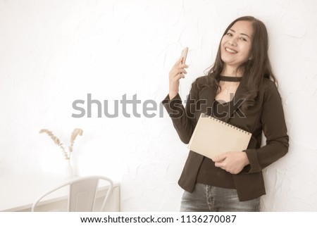 Portrait of a confident woman holding mobile phone and note book