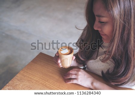Closeup image of an asian woman holding a cup of hot coffee before drinking with feeling good in cafe