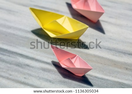 Pink and yellow paper folded, origami, boats on a rock, copy space