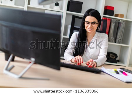A young girl is sitting at the table and typing text on the keyboard.