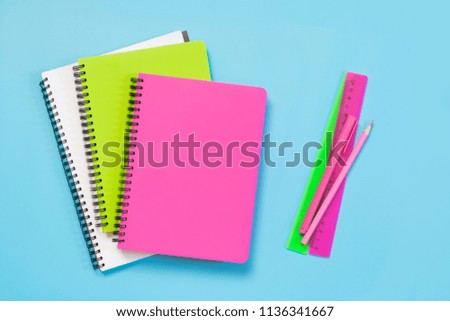 Colorful girlish school supplies, notebooks and pens on punchy blue background. Top view, flat lay. Copy space.