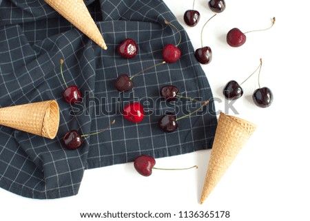 Ice cream concept Fresh cherries and waffle cone on checkered napkin Ice cream spoon White backgroud Summer fruits Harvesting Organic fruits Copy space Top view