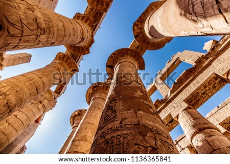 Ancient ruins and hieroglyphs at Karnak Temple, Luxor, Egypt.
View from the ground to the high pillars.
 Royalty-Free Stock Photo #1136365841