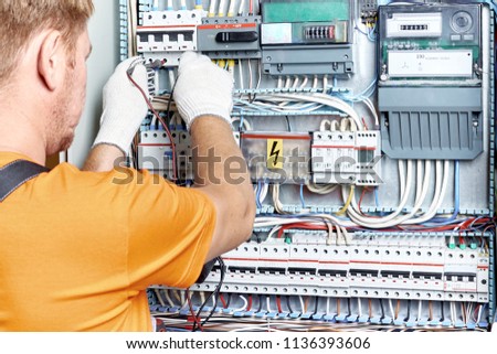 The electrical engineer checks the parameters of the electrical panel at the industrial site. Royalty-Free Stock Photo #1136393606