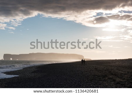 Black Beach and Sea-stacks in Vik Iceland, most popular beach in Iceland with couple walking along sea side