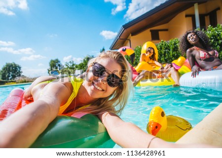 Multiracial group of friends having party in a private villa with swimming pool - Happy young people chilling with shaped air mattresses
