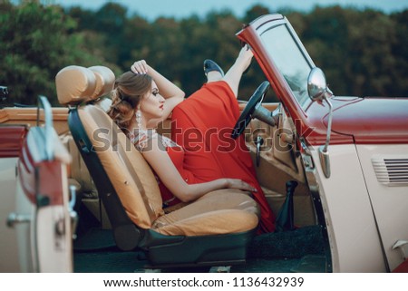Elegance lady in a red dress sitting in a red retro car
