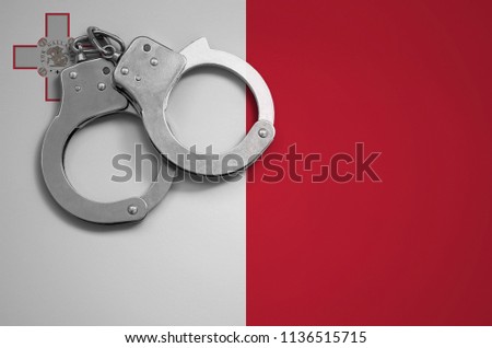 Malta flag  and police handcuffs. The concept of crime and offenses in the country