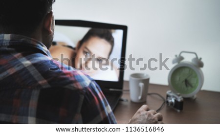 Back view of male photographer working at home on laptop, retouching photos