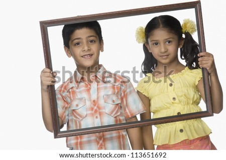 Portrait of a girl and a boy holding an empty picture frame