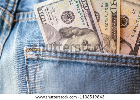 U.S. dollars in the back pocket of blue jeans. close-up. U.S. 100, 20 and 5 dollar bills. Banknotes of US dollars sticking out of a pocket of jeans. American currency.