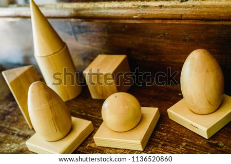 Solid wood shapes to study geometry and volumes, cones, triangles, squares, spheres on a warm wood background.
