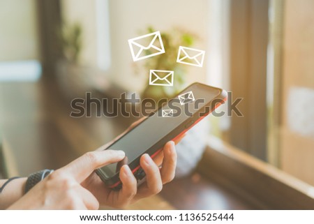 Woman hand using smartphone to send and recieve email for business on nature green bokeh vintage color tone background.